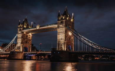 Fototapeta na wymiar tower bridge at night with intense and dark clouds. tower bridge lit above the thames river in the dark and cloudy night
