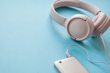 Earphones with smartphone on blue background