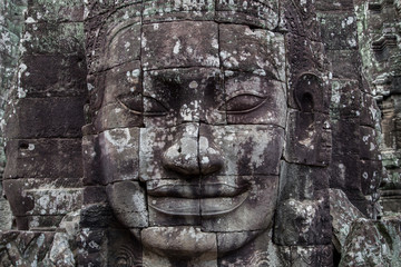 Stone carved Buddha face on ancient khmer Bayon temple in Angkor Wat complex near Siem Reap,...