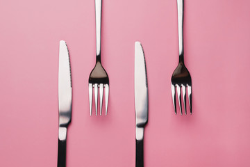 Silver Forks and knifes isolated on pink background. It's lunch time concept. 