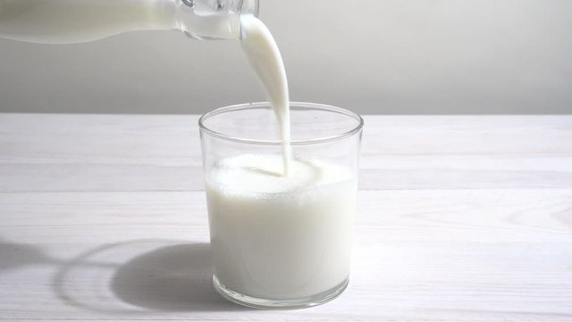 Vertiendo leche en un vaso en la mesa