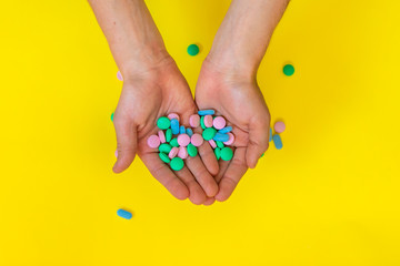 Medical colourful pills at kid's hands on yellow background