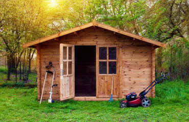 Hovel after work in evening, golden hour. Garden shed (front view) with hoe, string trimmer,  rake...