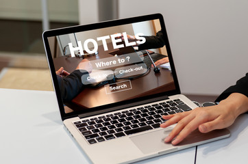ノートパソコンでホテルのオンライン予約検索の画面と女性の手