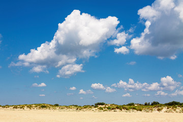 Cumulus clouds in the blue sky above the sand hills