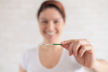 Happy woman shows a positive pregnancy test. The concept of female fertility. Human chorionic gonadotropin. Two stripes expecting a baby.