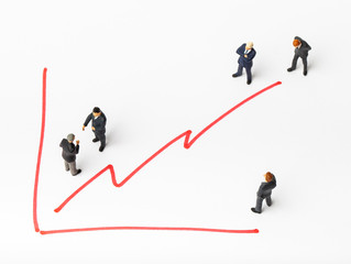 Miniature people on paper with painted financial chart.