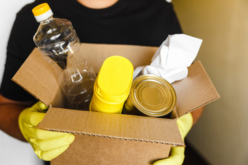 man in yellow rubber gloves keep brown cardboard box with plastic paper and metall rubbish on black...