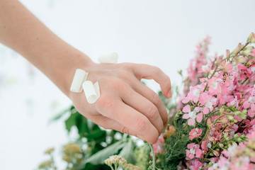 Fototapeta premium Hand of a florist girl makes a bouquet of flowers. Pink flower. Vintage home decor background. Selective focus.
