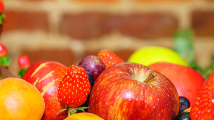 Set of berries and fruits in wooden box. Apple, strawberry, grape, berry and peach on a defocused...