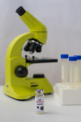 Anti-COVID-19 vaccine, microscope and tubes. Portrait orientation. White background.
