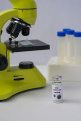 Anti-COVID-19 vaccine, microscope and tubes. Portrait orientation. White background.
