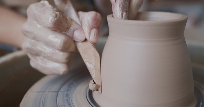 Female potter makes a pot on the pottery wheel.