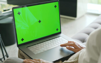 Mock Up Green Screen laptop on woman legs sitting on sofa in living room