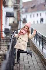 Fototapeta premium girl dressed in winter clothes walks along an old street