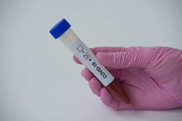 A hand holding a tube with blood positive COVID-19. Coronavirus test. horizontal orientation. White background.