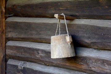 A wooden bucket hangs on the wall of the barn.