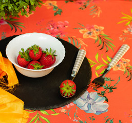 red strawberry on spoon accompanied by more strawberries