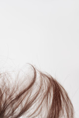 Part of the loose brown hair on the edge of the frame on a white background. Beautiful copper hair lies on a light gray background. Background or texture for a hair salon