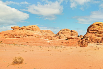Fototapeta na wymiar Rocky formations and mountains in sandy desert, blue sky above, typical scenery in Wadi Rum, Jordan