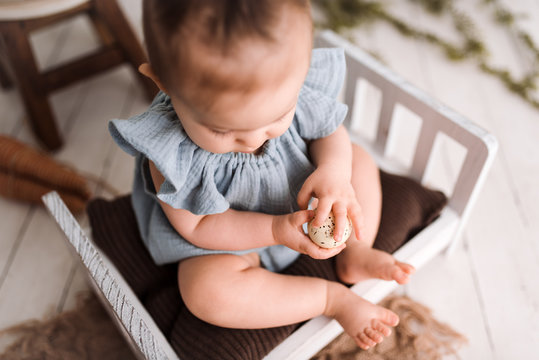 Cute Baby Girl On Easter Set In A Studio Wearing A Blue Onsie 