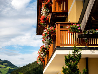 Potted flowers on balconies and terraces of wooden Austrian chalets in the small village of Grossarl. Classical tourism to Austria. Beauty, comfort and harmony. Clean air and quiet life in the Alps.
