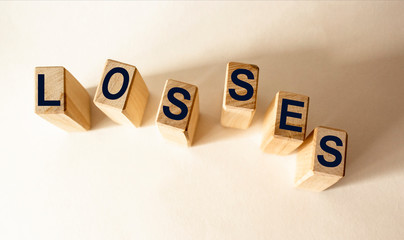 Wooden cubes with word LOSSES on wooden table. Financial loss or unprofitable busines ventures...