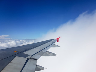 Obraz premium From the window of the plane in mid-flight you can see its wing between clouds in an intense blue sky.