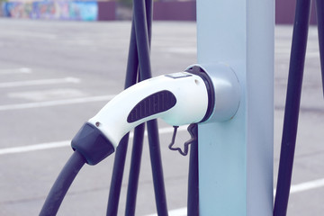 Power supply for electric car charging. Electric car charging station. Close up of the power supply plugged into an electric car being charged.