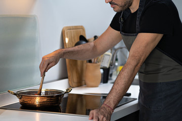 chef man cooking mixing food in vintage textured copper cooking at home on kithcen stove