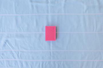 Pink sponge for dishes on a blue background. Card with copy space for text