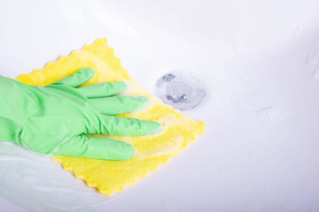 hand with a rag cleans the sink in the bathroom