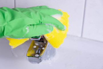 woman cleans the tap in the sink in the bathroom