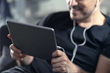 man holding using digital tablet and headphones sitting on a sofa. Online education, working, video...