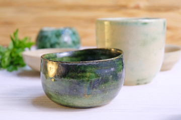 Modern pottery. Decorative ceramic, clay plate. Handmade light pottery.  Set of ceramic, bowls, cup with background.