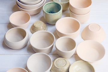 Modern pottery. Decorative ceramic, clay plate. Handmade light pottery.  Set of ceramic, bowls, cup with background.