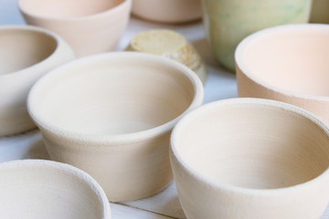 Modern pottery. Decorative ceramic, clay plate. Handmade light pottery.  Set of ceramic, bowls, cup with background.