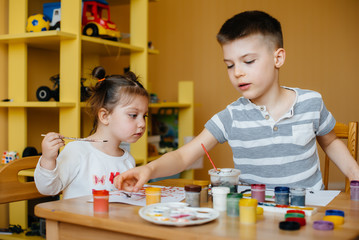 Fototapeta premium A boy and a girl play together and paint. Recreation and entertainment. Stay at home