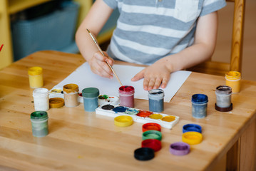 A cute little boy is playing and painting in his room. Recreation and entertainment. Stay at home