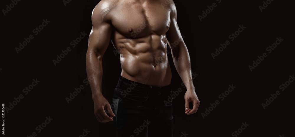 Wall mural Muscular model sports young man on dark background. Fashion portrait of strong brutal guy. Sexy torso. Male flexing his muscles. Sport workout bodybuilding concept.