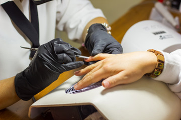 Manicurist work on a woman client hands, Professional works in gloves for sterility