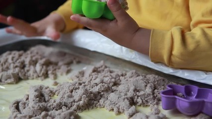 The boy is playing in his room. Educational game. A child plays kinetic sand in quarantine. Development of fine motor skills in children - Powered by Adobe
