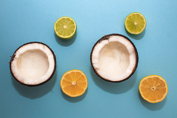 Two halves of coconut, slices of lemon and lime on a blue background. Summer fresh fruit concept