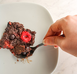 Chocolate brownie slice with female hand taking a bite. Vegan brownie.