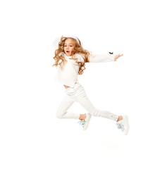 A girl with long hair, dressed in white colored clothes, is jumping on a white background.