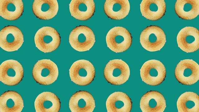 Rotating a lot of pink donuts on green background for any purposes. National Donut Day. Doughnut 3d model. Sweet junk food.