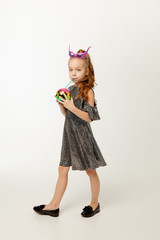 Little girl in sequin dress drinks a drink through a straw