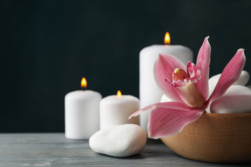 Candles, orchid and stones on wooden table. Zen concept