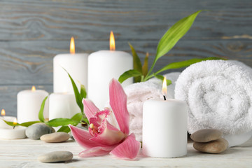 Fototapeta na wymiar Composition with candles, towels, stones and orchid on wooden table. Zen concept