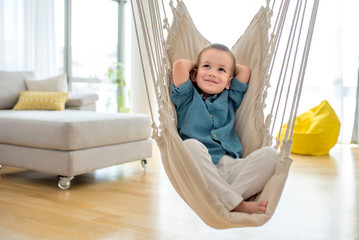 Adorable little boy in comfortable indoor swing relaxing and thinking - Powered by Adobe